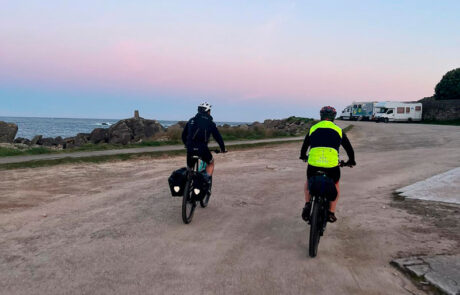 dos ciclistas cerca del mar acercándose a dos caravanas