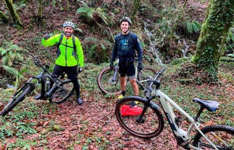 Dos ciclistas parados en el bosque, se ven tres bicis